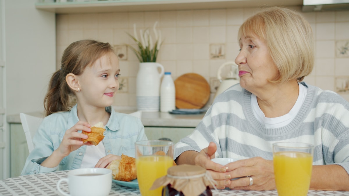 Großmutter und Enkelin frühstücken gemeinsam am Küchentisch